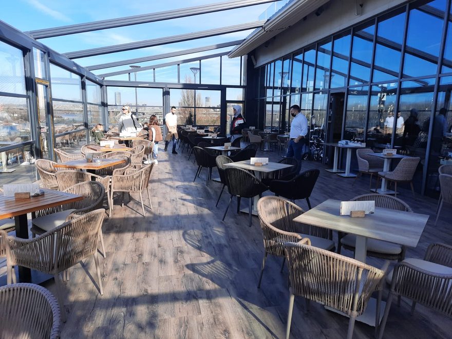 Wintergarten eines Restaurants mit Tischen auf Boden in Holzoptik