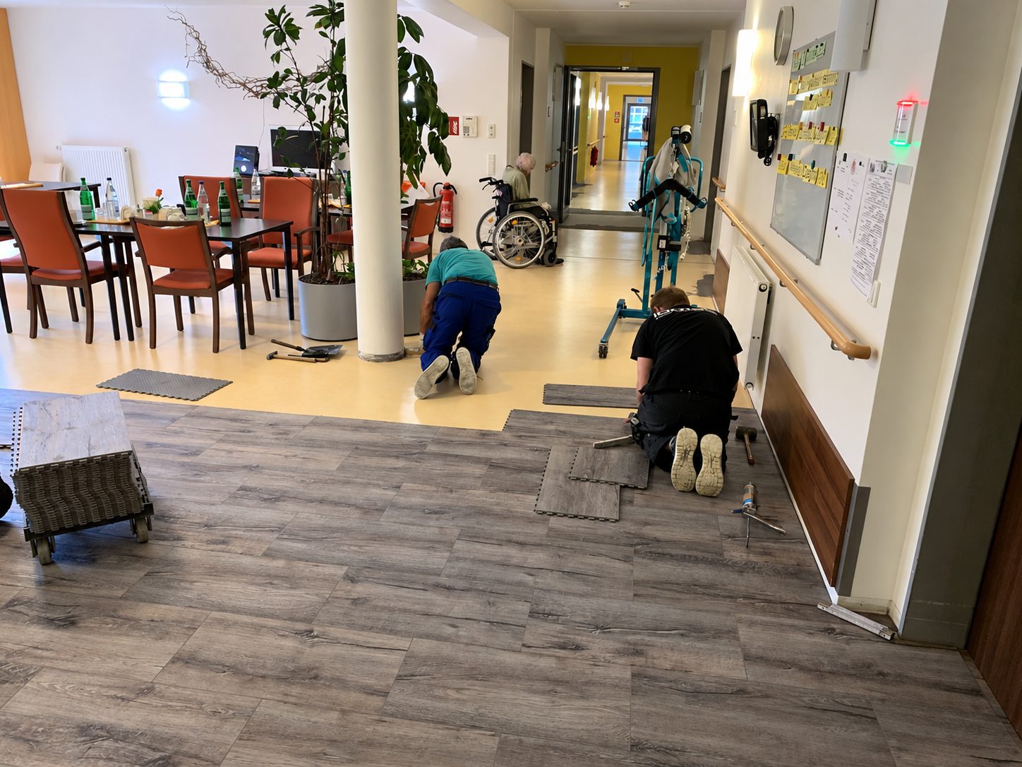 Verlegung eines Bodens in Holzoptik in einem Aufenthaltsraum während des Betriebs