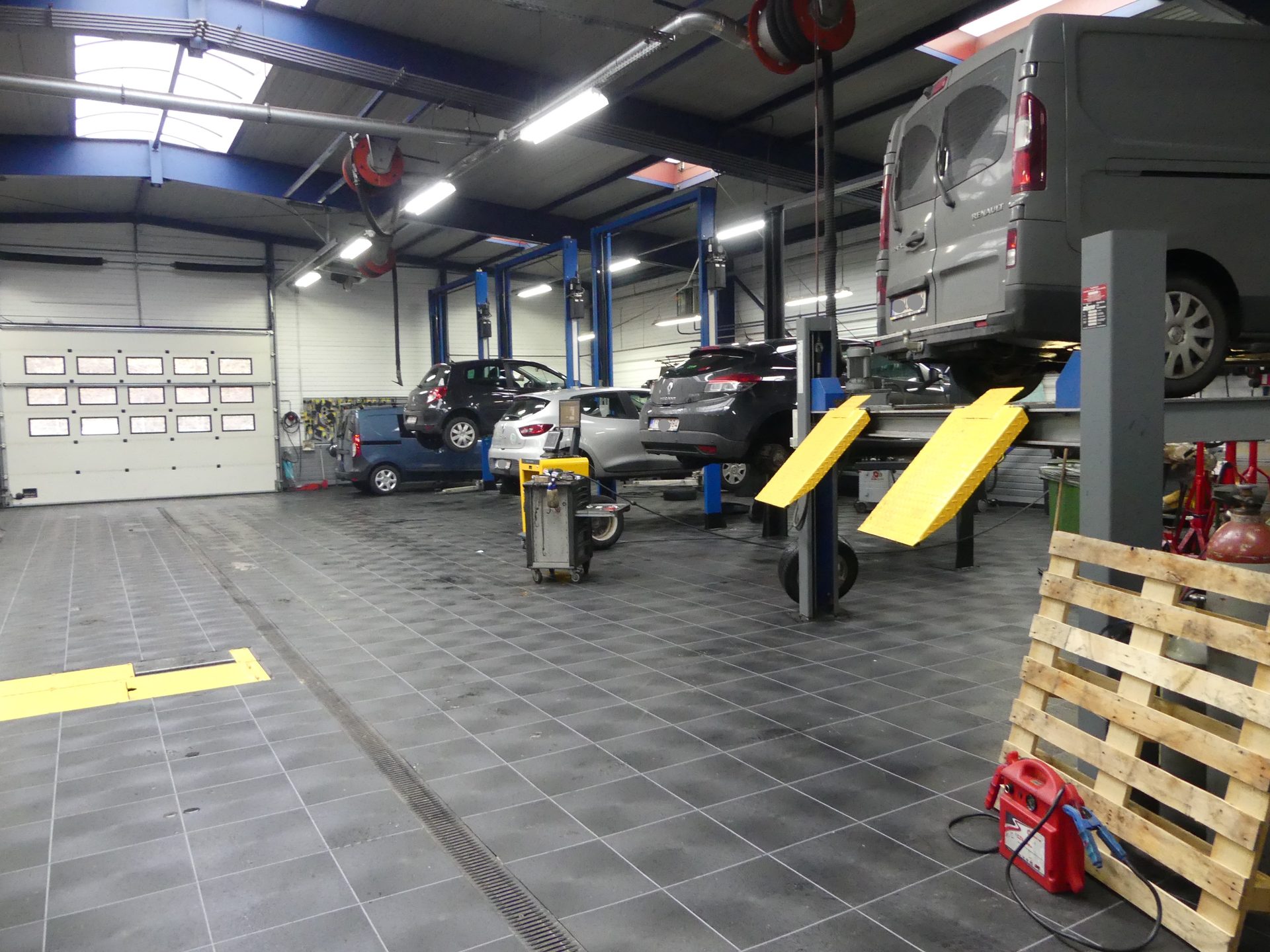 Kfz-Werkstatt mit Hebebühnen und Transporter auf dunkelgrauem Bodensystem