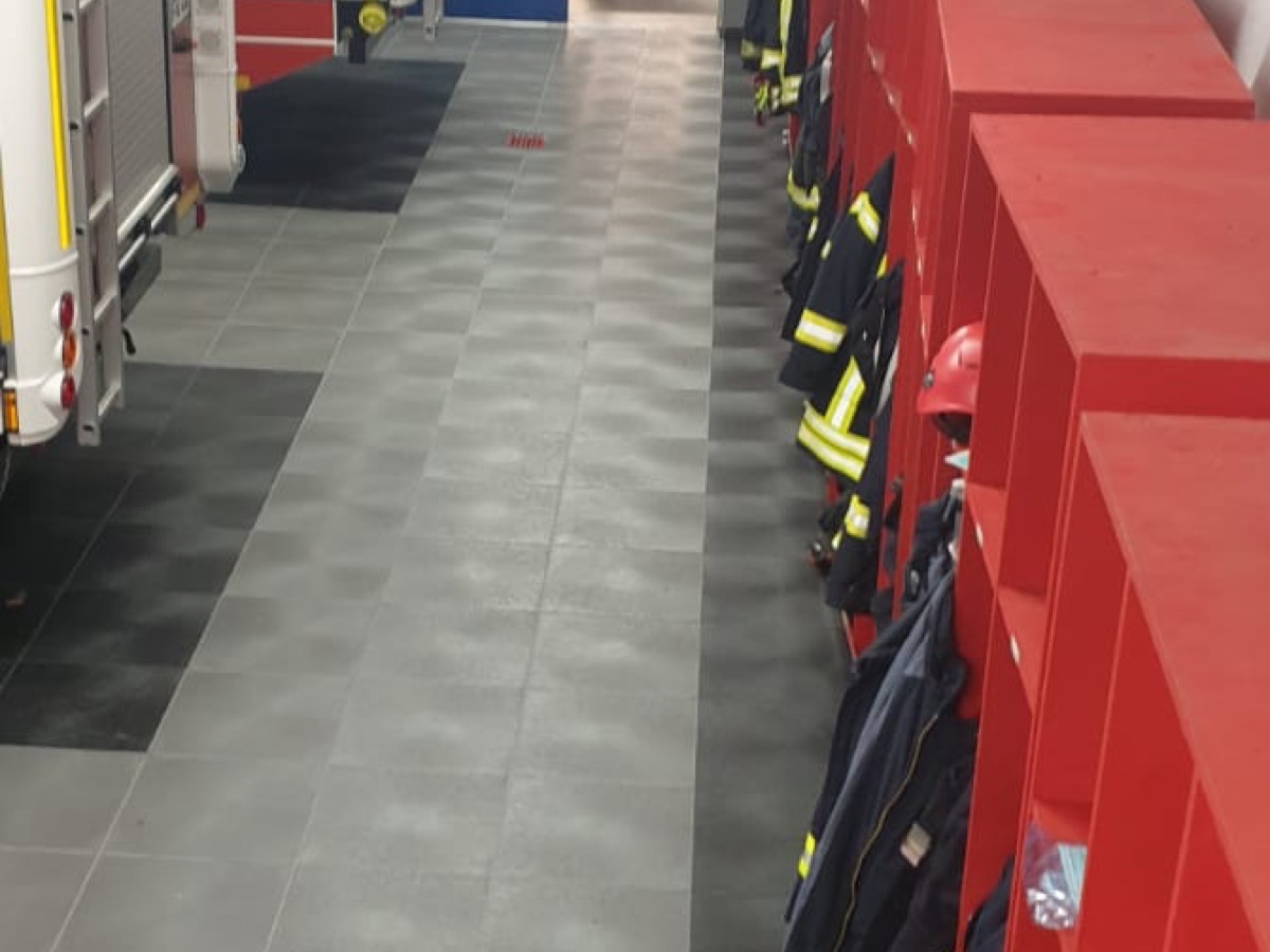 Fahrzeughalle einer Feuerwache, Löschfahrzeug auf grauem Klick-Boden