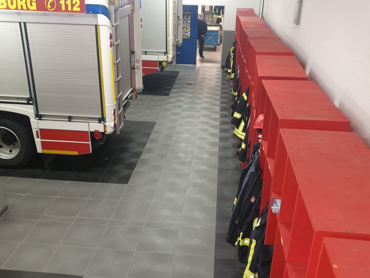 Löschfahrzeug neben roten Spinden, davor der graue Klick-Boden