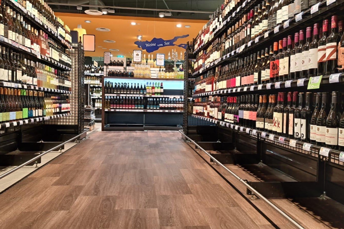 Weinregale beidseitig eines Gangs mit warmem Boden in Holzoptik