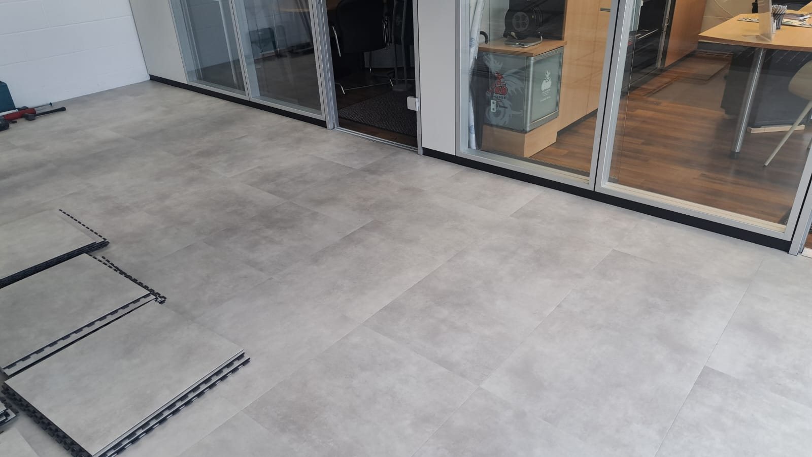 Derselbe Raum während der Verlegung, der neue Boden in Betonoptik liegt zum Teil, am Rand stapeln sich die nächsten Platten