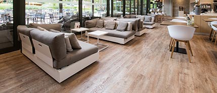 Wohnraum mit Sofalandschaft und warm-eichenfarbenem Designvinyl